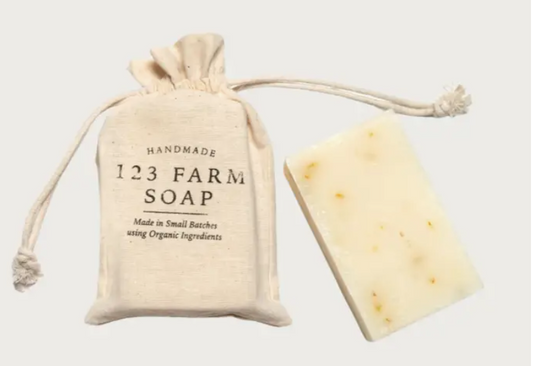 Handmade pink grapefruit soap with a drawstring bag labeled '123 Farm Soap' on a light background