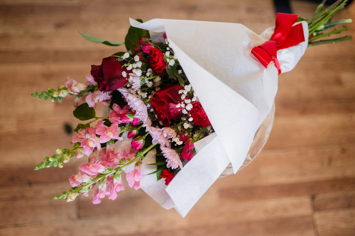 Bouquet of flowers with red and pink colors on a wooden surface