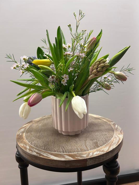 Floral arrangement on a decorative stand against a plain background